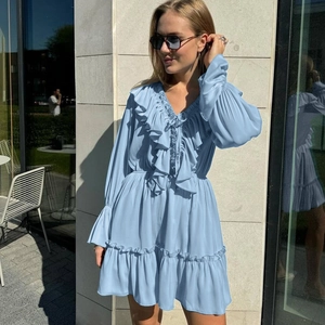 Detail of light blue V-neck dress with layered ruffles and elasticated flared sleeves