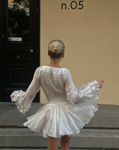 Rear view of white chiffon two-piece set featuring layered ruffle sleeves and pleated skirt