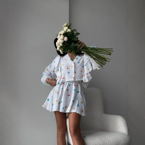 Detail view of white two-piece set with colorful heart print and ruffled shirt edges