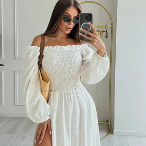 Detail of smocked texture and off-shoulder long sleeves on a white bohemian dress