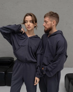 Détail du sweat à capuche gris foncé avec coutures apparentes et logo Backstage gaufré