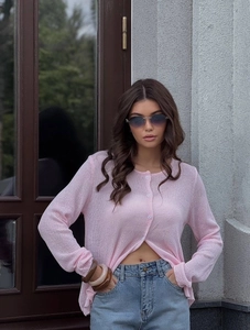 Detail of light pink knit cardigan with delicate buttons and long sleeves on model