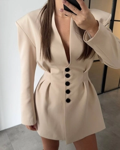 Detail view of beige blazer dress featuring large black buttons and pleated waist