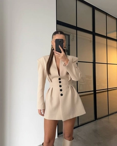 Detail showing the pleated waist and five black buttons of this beige blazer dress
