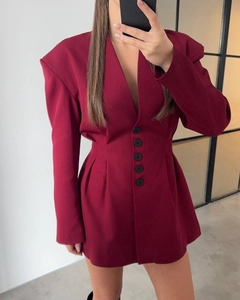 Detail of burgundy blazer dress featuring deep V-neck, waist buttons and long sleeves