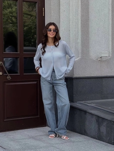 Light blue loose knit cardigan and high-waist jeans shown in a stylish street style pose