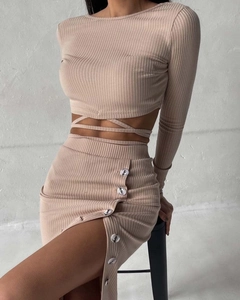 Detail of apricot ribbed knit fabric with decorative side buttons and side slit