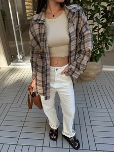 Women's brown plaid shirt styled with beige crop top and high-waist white jeans set