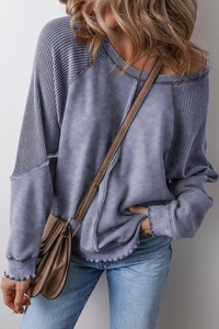 Detail of blue-grey waffle knit texture and washed fabric panels on a casual long-sleeve tee