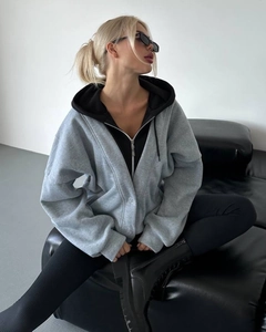 Detail eines grauen Lagen-Kapuzenpullis mit Reißverschluss und modernem Streetstyle