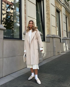 Detail of elegant beige wool coat with wide lapels and large side pockets on a model