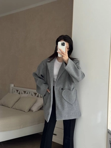 Detail of grey wool coat featuring unique heart-shaped side pockets and notched lapels