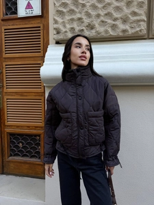Detail of dark quilted jacket showing stand collar, snap buttons and diamond stitching
