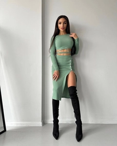 Detail of mint green ribbed knit midi skirt featuring high slit and metal buckle accents