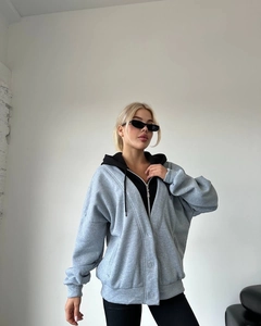 Detail eines grauen Oversized-Zipp-Hoodies mit schwarzem Lagen-Look-Kapuzendesign