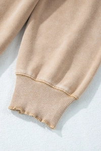 Detailed close-up of distressed ribbed cuffs on a vintage washed tan cotton T-shirt