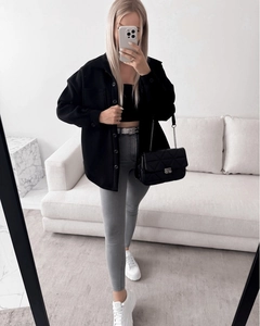 Close-up of a stylish quilted chain shoulder bag paired with a thick black shirt jacket