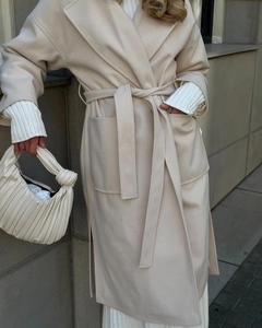 Detail of elegant beige wool coat featuring a wide lapel and waist drawstring tie