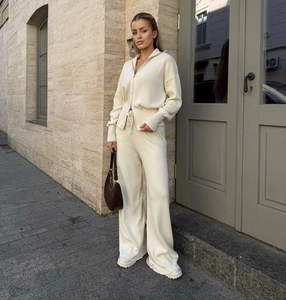 Dettaglio di un set in maglia beige con cardigan a coste con zip e pantaloni larghi abbinati