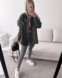 Detail of a dark grey oversized button-up shacket with large chest pockets and lapel collar