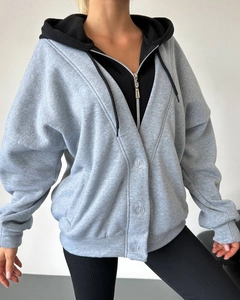 Detailansicht eines zweilagigen Kapuzenpullovers mit grauer Knopfleiste und schwarzem Zipper