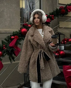 Outdoor shot of brown teddy fur coat with black belt and fuzzy white earmuffs