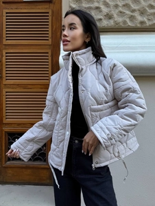 Women's quilted beige winter puffer jacket featuring high stand collar and drawstring hem