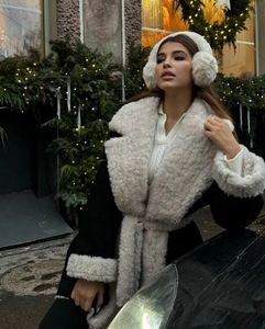 Detailed view of women's winter coat featuring thick white shearling trim on collar and cuffs