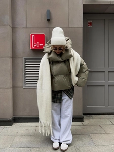Détail d'une doudoune courte vert olive avec écharpe et tenue d'hiver superposée stylée