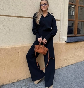 Dettaglio del completo in maglia nera con maglione a mezza zip e pantaloni larghi