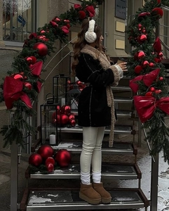 Winter outfit detail showing warm shearling snow boots and fluffy earmuffs on a festive stairs