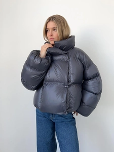 Détail d'une doudoune oversize à col montant avec une finition satinée gris foncé