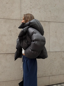 Détail de la doudoune noire oversize avec tissu brillant et design à col montant haut