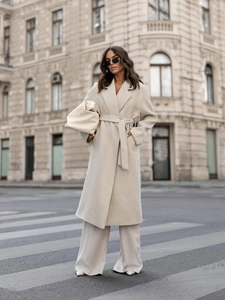 Outdoor street style shot of a beige long wool coat with large lapels and waist belt