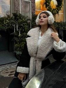 Women's warm shearling trimmed coat with belt and plush earmuffs in winter street scene