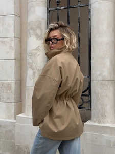 Detail of khaki drawstring waist trench coat with stand collar and loose back profile