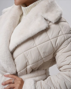 Gros plan d'une veste matelassée crème avec col en fausse fourrure et motif en losanges