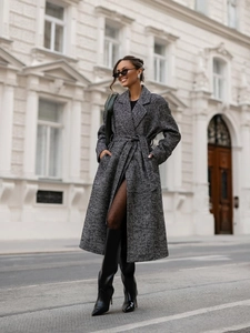 Street style shot of a long herringbone wool coat with lapels and belted waist detail