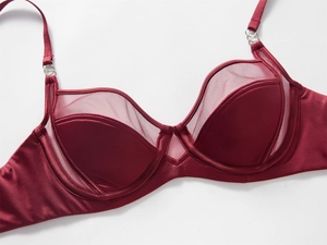 Dettaglio del reggiseno in raso bordeaux con inserti in mesh e spalline