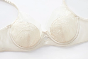 Close-up of cream lace embroidery and silk satin texture on underwired full cup bra