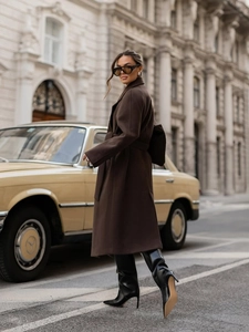 Detail of elegant dark brown wool coat with waist belt and notch lapels in city street