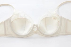 Macro detail of beige lace bra featuring floral embroidery and U-shaped underwire support