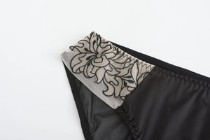 Detail view of exquisite vintage floral embroidery on black sheer lace and satin underwear