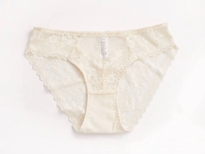 Detail shot of cream white lace panties with wave edge design and soft cotton crotch fabric