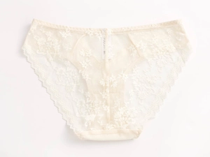 Close-up of floral lace texture and scalloped edges on cream low-rise women's briefs