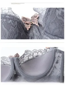Dettaglio reggiseno in pizzo grigio con ricami floreali, fiocco rosa e ciondolo a C