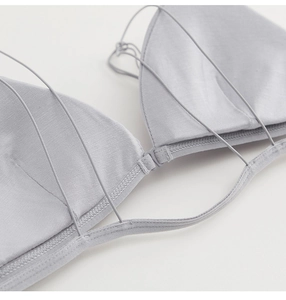 Detalle de bralette de satén plateado con hebilla delantera y diseño de múltiples tiras