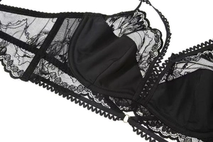 Close-up of black lace bra detail with intricate floral patterns and silver metal buckle