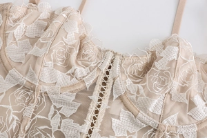 Detalle de bordado floral beige y malla semitransparente en un corpiño de estilo retro