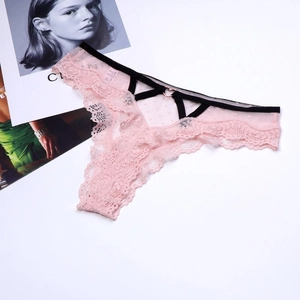 Détail de culotte en dentelle rose avec résille à pois, bretelles noires et boucle cœur